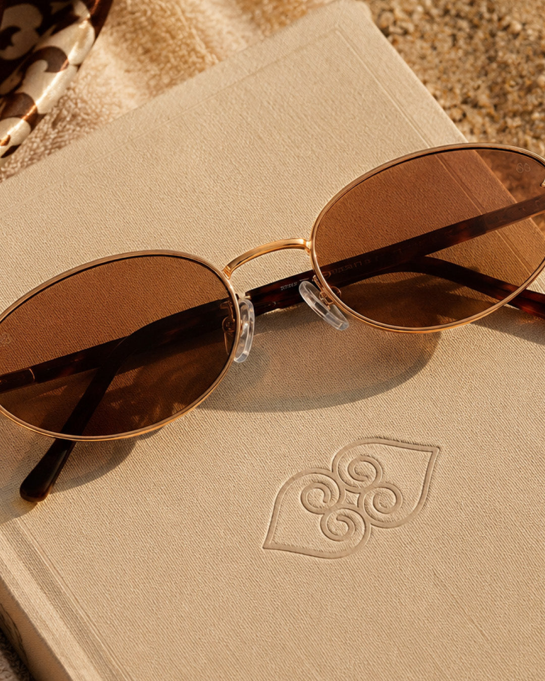 Miel sunglasses on embossed notebook — golden hour